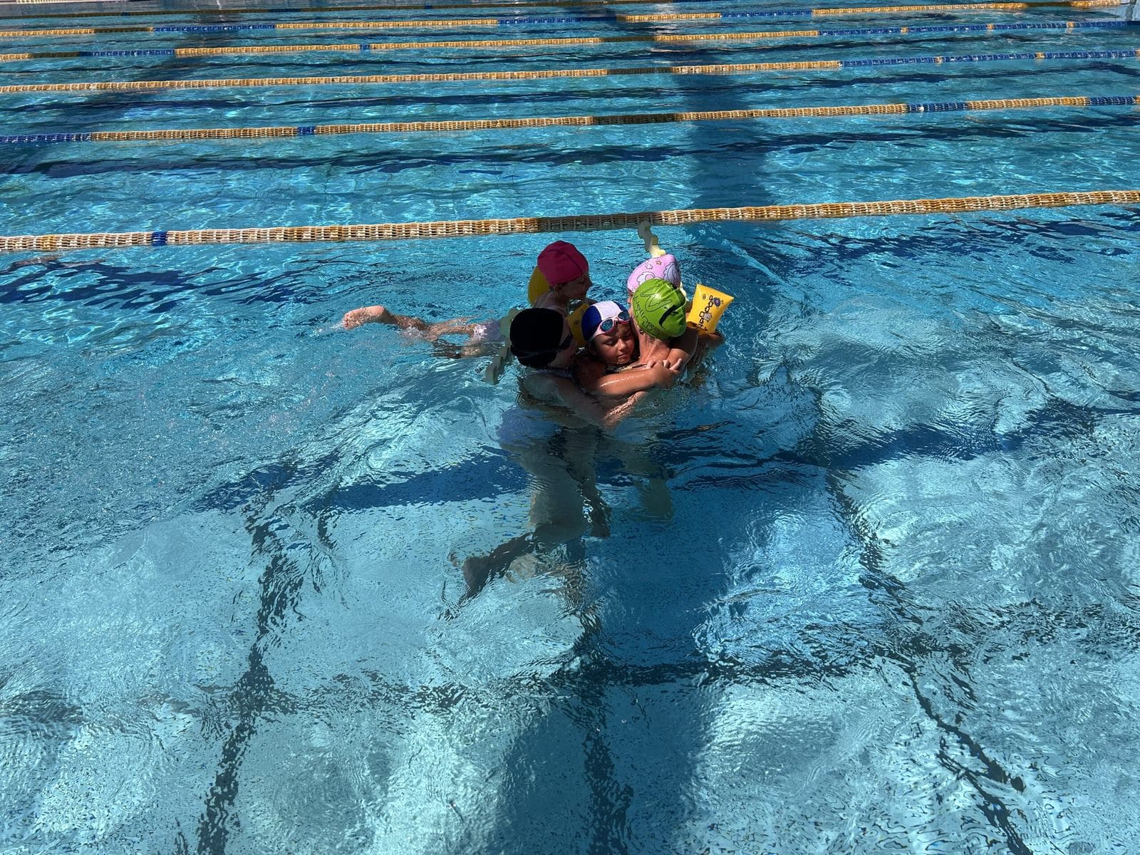 Un'istruttrice sostiene due bambini in acqua nella piscina di Wellness Town